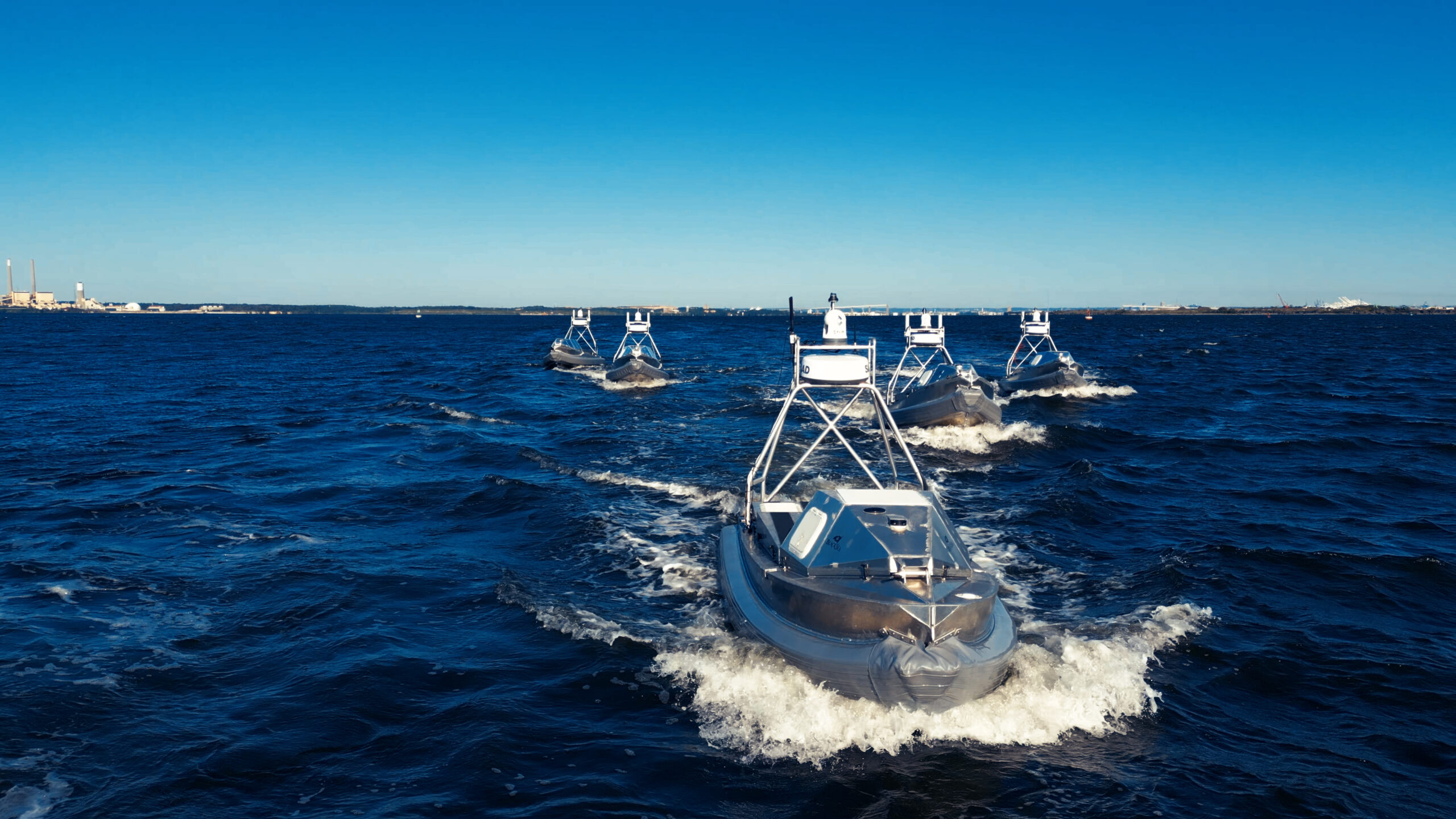 Fleet of Global Autonomous Reconnaissance Craft (GARC) unmanned surface vessels operating in formation at sea, equipped with Doodle Labs Helix radios for extended-range mesh command and control.